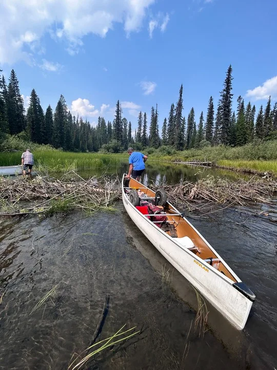 A canoe in the shallow water of Babcock Creek beside a beaver dam