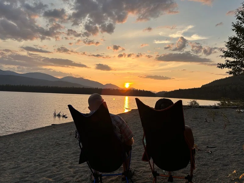 Two camp chairs on a beach at sunset on the Bowron Lake Circuit