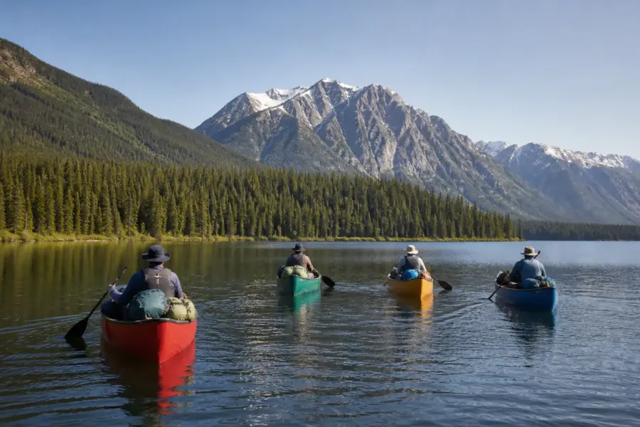 Four canoes paddling together across a calm lake on the Bowron Lake Circuit