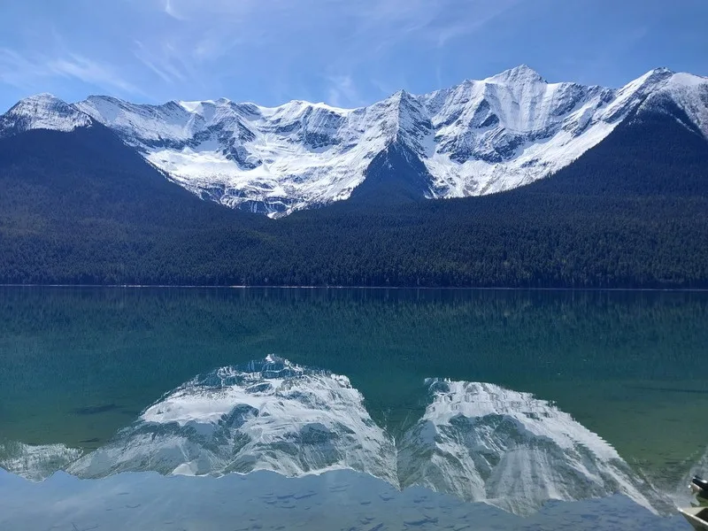 Snow-covered peaks reflected in the turquoise water of a Bowron Lake Circuit lake