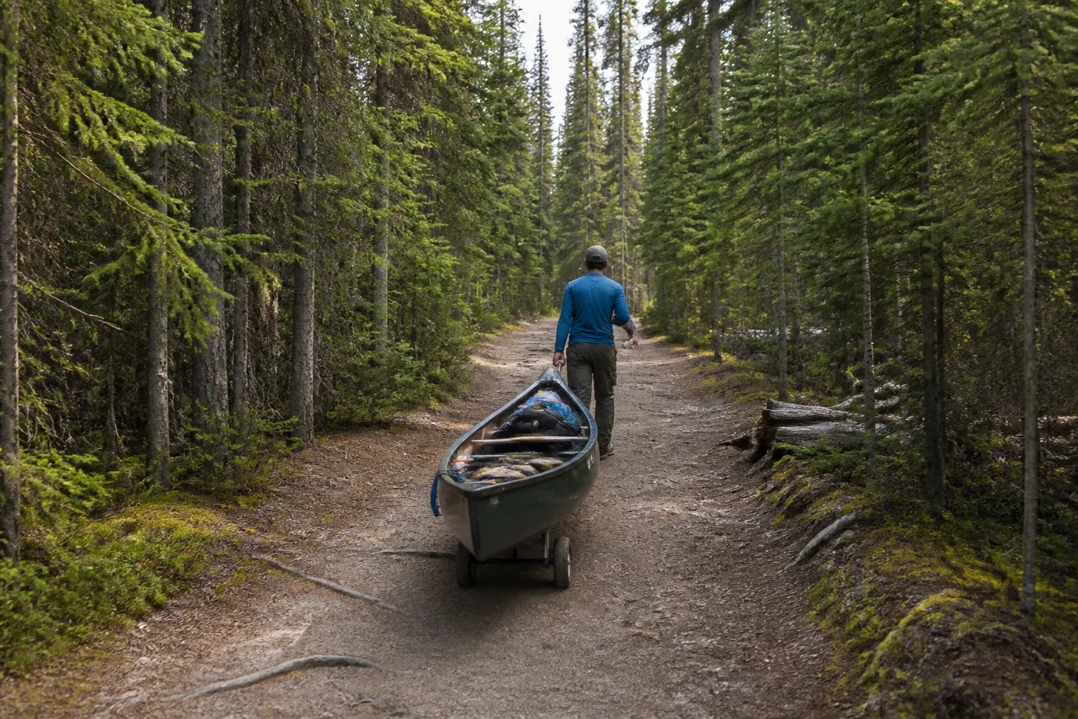 A canoe on a cart being towed along the first portage trail from the Registration Centre