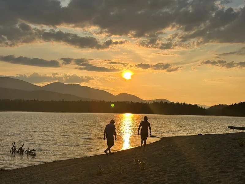 Two people walking a sandy beach at sunset on the Bowron Lake Circuit
